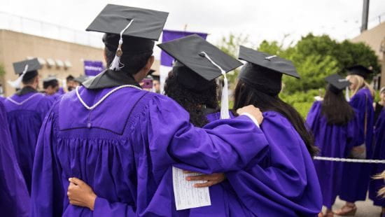 A group of Northwestern seniors in graduation gowns hugging each other and facing away from the camera