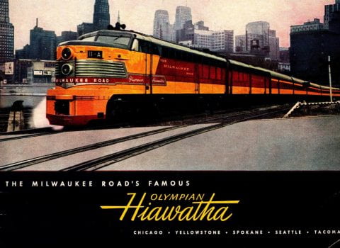 photograph of the Milwaukee Road's Hiawatha going through a large city with text Milwaukee Road's Famous Olympian Hiawatha - Chicago - Yellowstone - Spokane - Seattle - Tacoma