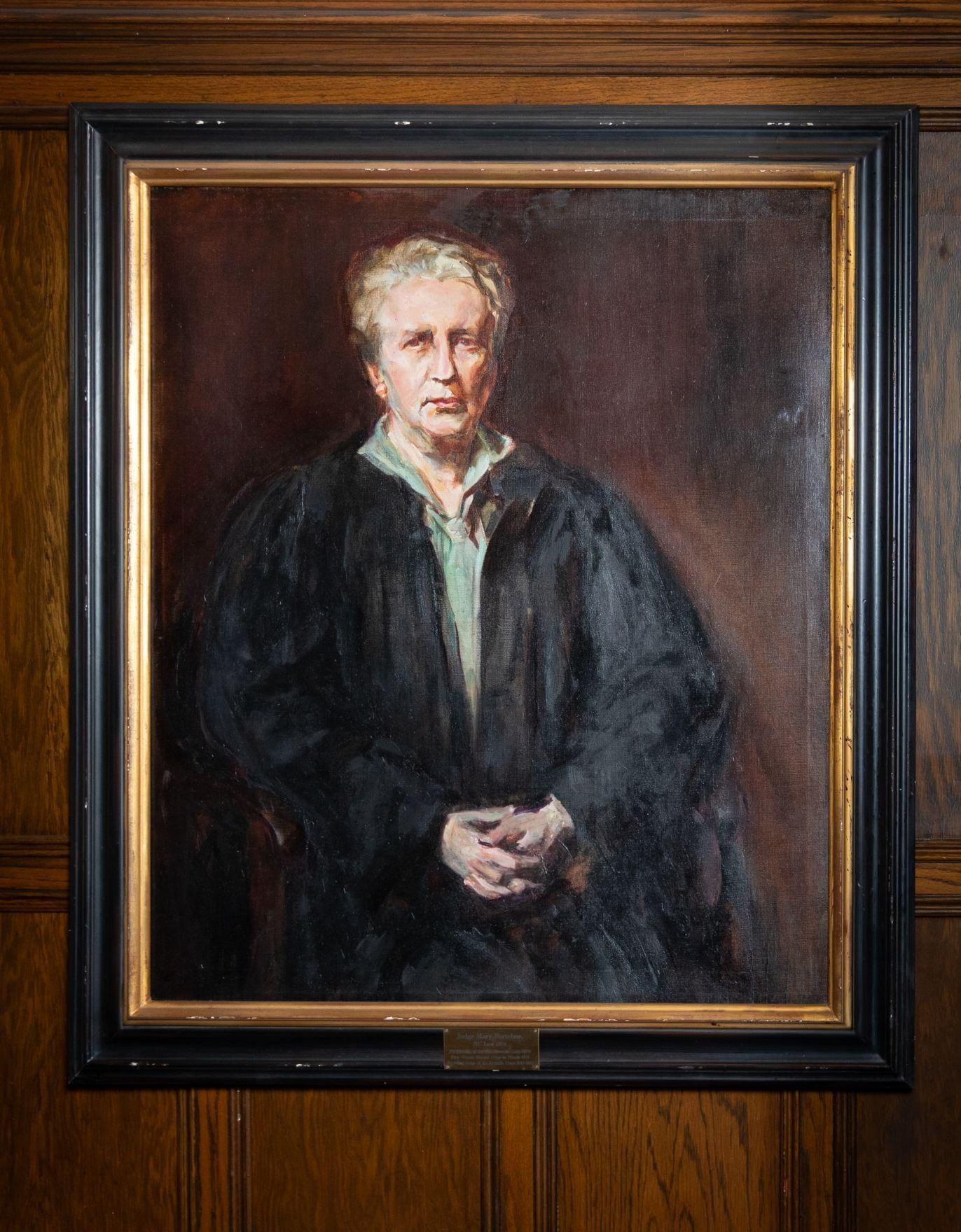 Straight-face woman in black judicial robes and light green blouse. 