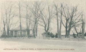 image of Lincoln Park's artesian well with a group of cyclists gathered under trees 