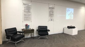 An angled photo of the entrance hall of Northwestern Main Library. A projector projects an image on the wall and two panels with descriptive text are displayed.