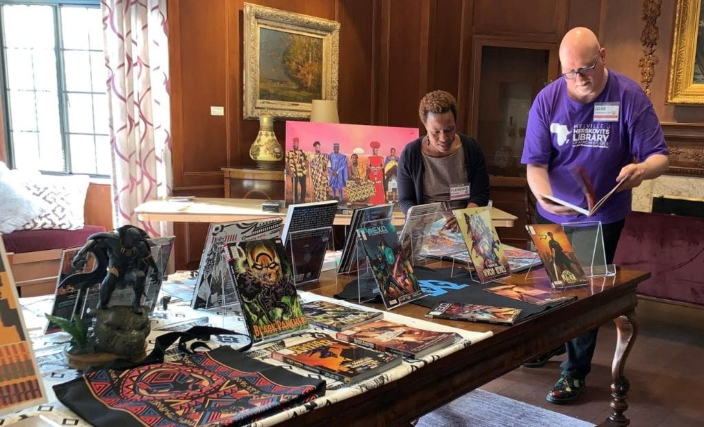 Gene Kannenberg and African Studies librarian Florence Mugambi setting a table of Black Panther related materials at the 2018 Black Graduate Student Association Conference in Scott Hall