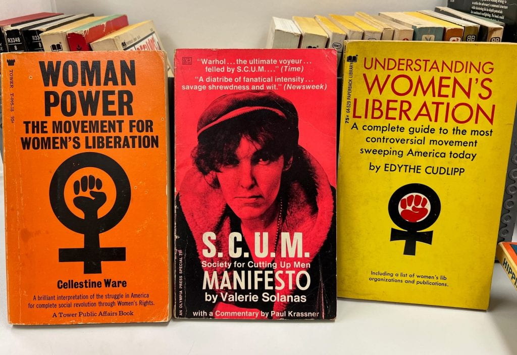 3 paperback books with brightly colored covers of orange, red, and yellow.