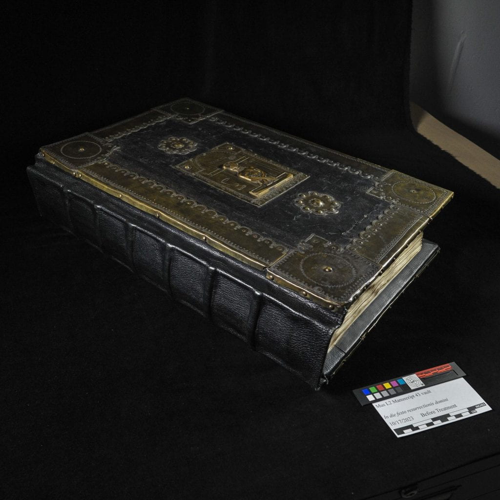 Heavy leather-bound book with brass decorative elements on a black background