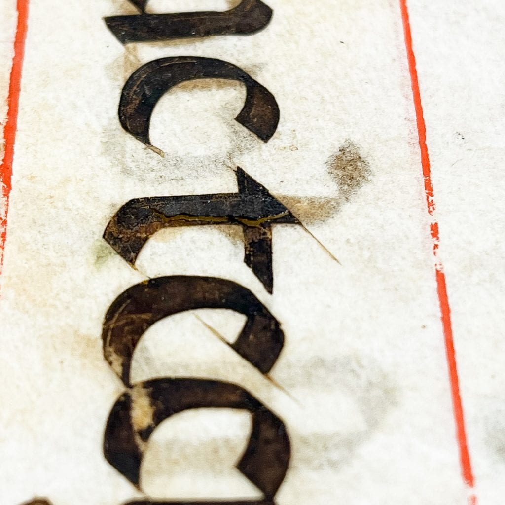 Detail of text on a page showing damage inside the black ink letters